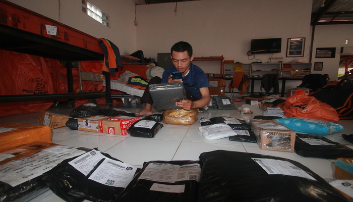 MENINGKAT: Petugas Pos Indonesia Jepara mensortir barang yang hendak dikirimkan ke pelanggan.