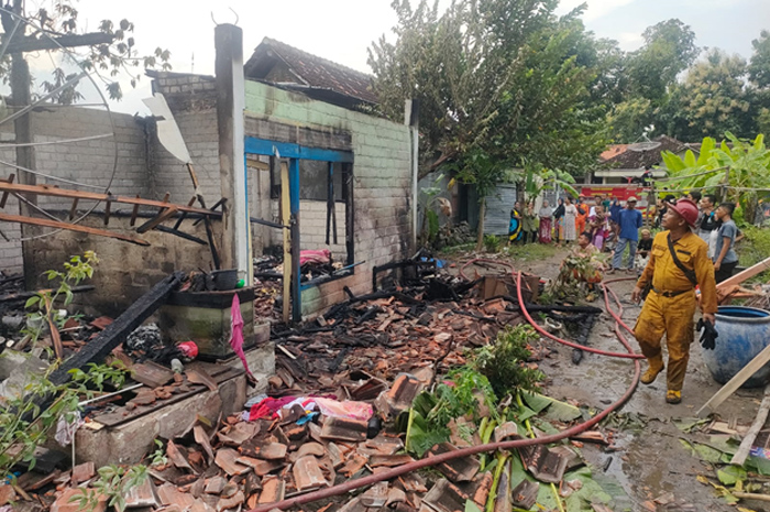 HANGUS: Petugas Damkar Rembang melakukan penyemprotan rumah Rudiyanto yang terbakar, kemarin.
