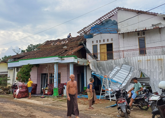 RUSAK: Warga coba membenahi atap yang telah jatuh setelah angin kencang menerjang rumah di Wedelan, Bangsri pada Minggu (21/4).