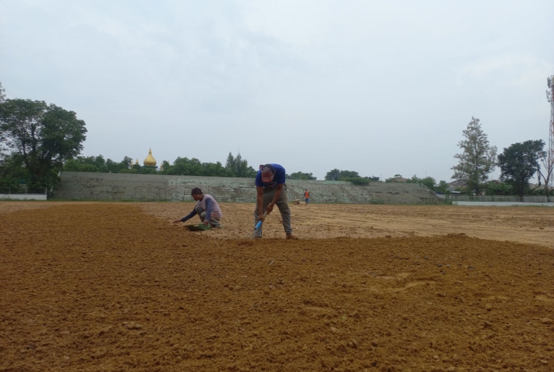 DIKEBUT: Pekerja meratakan permukaan lapangan Stadion Krida Bhakti Purwodadi sebelum ditanami rumput pada Selasa (23/4).