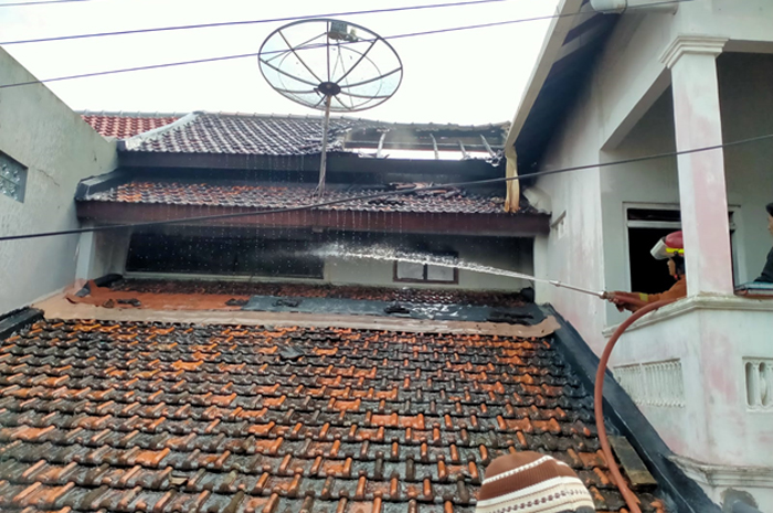 SENGIT: Petugas Pemadam Kebakaran berusaha melakukan pendinginan dari luar rumah yang terbakar kemarin.