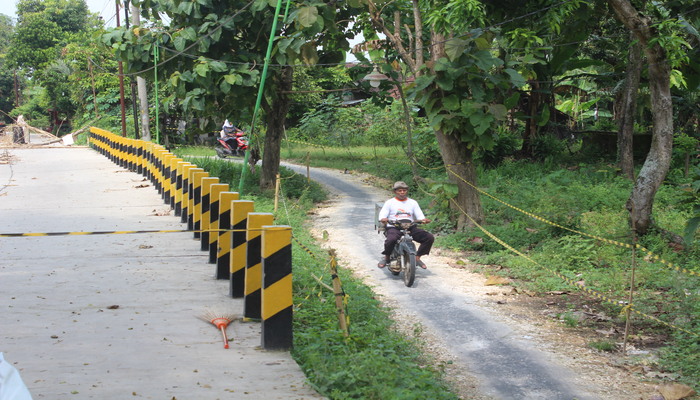 JADI SOLUSI: Pemotor melintasi jalan longsor Gadon dengan memanfaatkan jalur sementara yang dibuka warga.