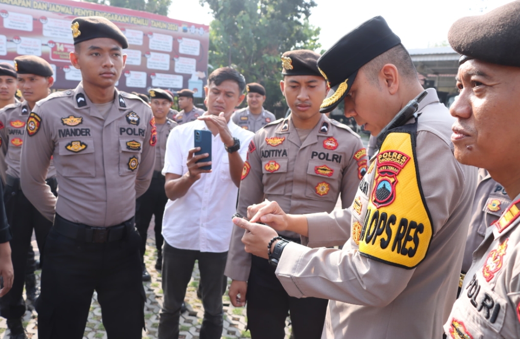 CEK HP: Wakapolres Grobogan, Kompol Gali Atmajaya memeriksa satu persatu handphone milik anggota usai apel pagi dalam pencegahan judi online pada Kamis (13/6).