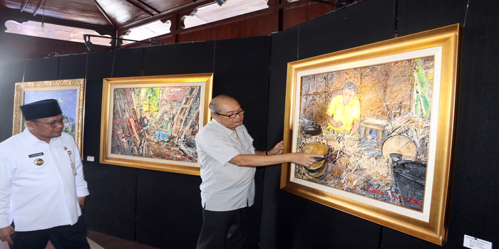 PRODUKTIF: JB. Iwan Sulistyo (kanan) menerangkan salah satu lukisannya tentang perajin caping kalo kepada Pj Bupati Kudus M. Hasan Chabibie saat pameran di area Pendapa Kudus bulan lalu.