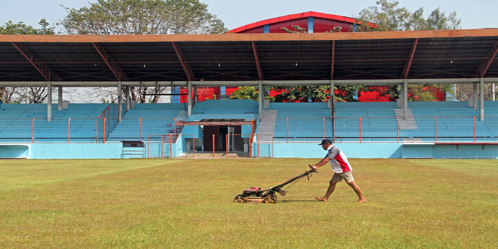 DIKEBUT: Pekerja memotong rumput Stadion Wergu Wetan dan warna tribun sudah berganti biru.
