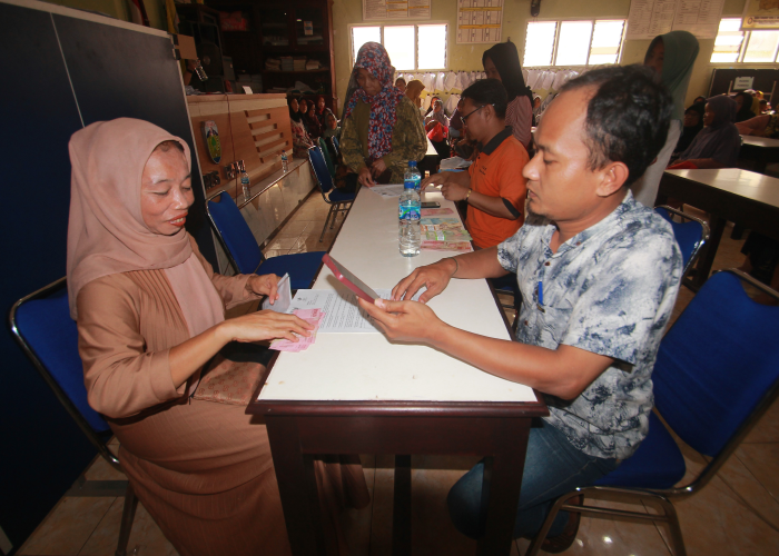 KEMBALI KE NEGARA: Sejumlah warga dilayani petugas Pos Indonesia saat mencairkan bantuan sosial belum lama ini.