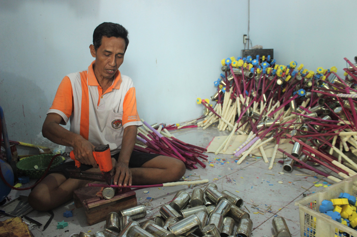 MENINGKAT: Seorang pengrajin merakit mainan anak tradisional yang jadi produk unggulan Kecamatan Welahan.
