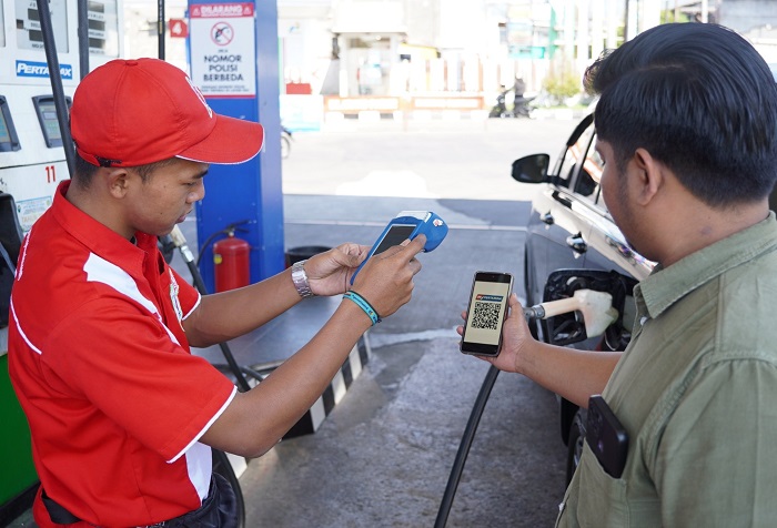 ATURAN BARU: Petugas SPBU menscan QR code dari handphone pembeli BBM jenis pertalite.