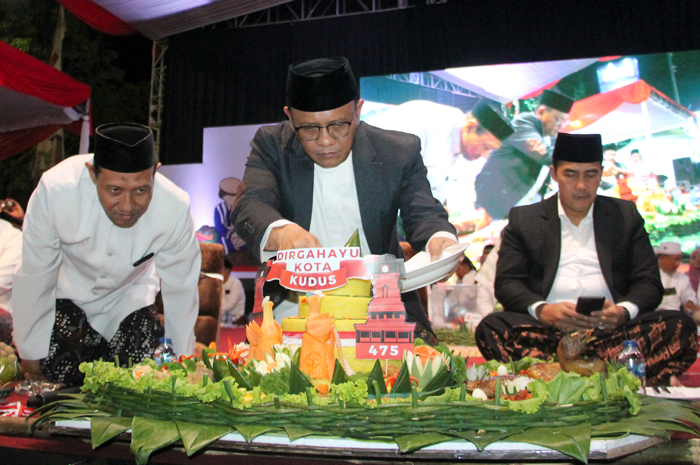 DIRGAHAYU KUDUS: Pejabat (Pj) Bupati Kudus, M. Hasan Chabibie memotong tumpeng dalam Kenduren Massal di Depan Pendapa Kudus tadi malam.