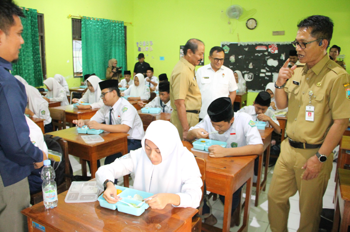 MAKAN BERSAMA: Sekda Kudus (kanan), Kedisdikpora Kudus (berdiri tiga dari kanan), dan Sekretaris Wantimpres RI Tim 5 Pelaksanaan Uji Coba MBG Nevy Dwi S meninjau uji coba makan gratis.