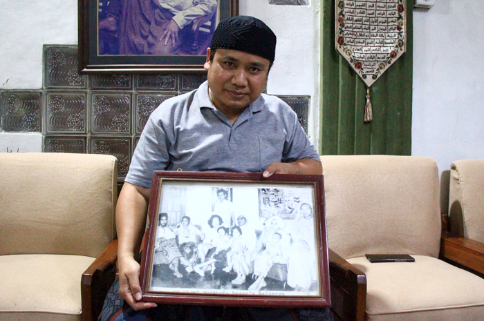 FOTO KELUARGA: Bisri Cholil Laquf membawa foto Mbah Bisri bersama keluarga