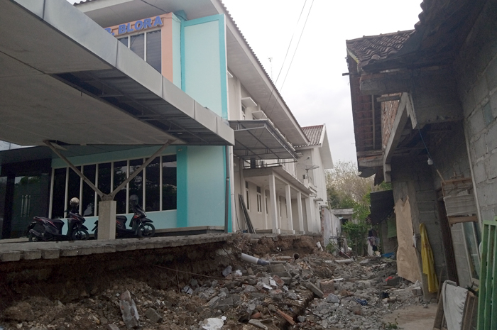 MEMPRIHATIKAN: Puing-puing tembok roboh yang masih berserakan di samping rumah warga.