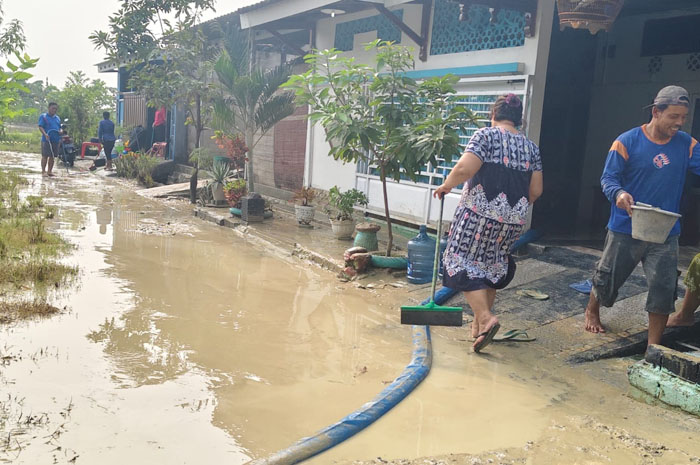 BERSIHKAN LUMPUR: Warga Perumahan Permata Hijau Kalongan, Kecamatan Purwodadi sedang membersihkan rumah dari lumpur usai terkena banjir bandang, Minggu dini hari (24/11).