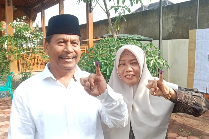 RAMPUNG NYOBLOS: Harno bersama istri menunjukkan tinta di jari kelingking setelah menyalurkan hak lilih di TPS 4 Sidowayah, Rabu (27/11).