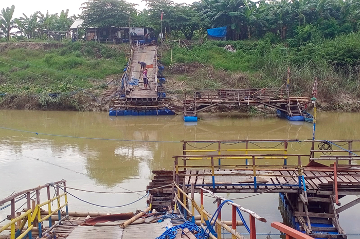 PERAWATAN: Jembatan apung diputus sementara, agar sampah bisa dapat terbawa aliran sungai dan sedang dalam proses pemasangan oleh pekerja kemarin.