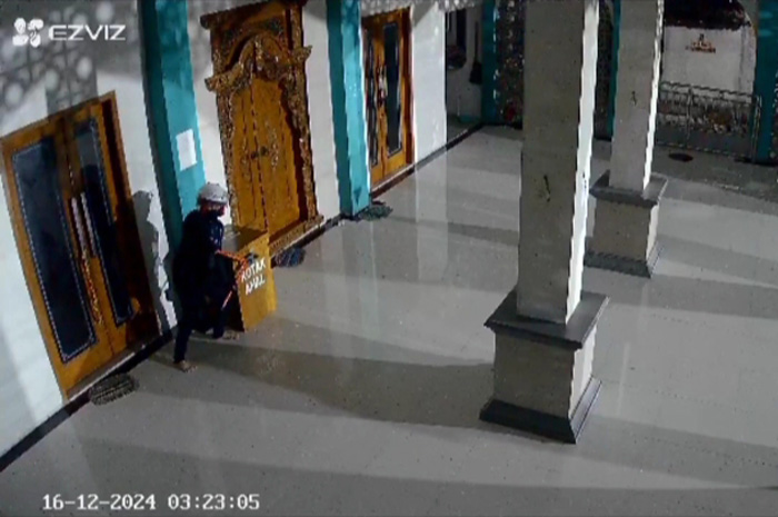 PENCURIAN: Tampak seorang pria mengenakan helm penutup kepala sedang mengangkat kotak amal masjid di Baturejo, Sukolilo.