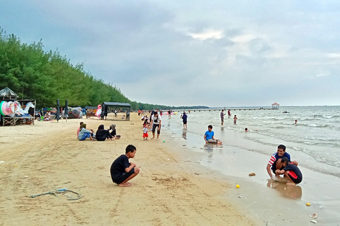 BERMAIN PASIR: Wisatawan Pantai Karangjahe tampak bermain pasir laut kemarin.