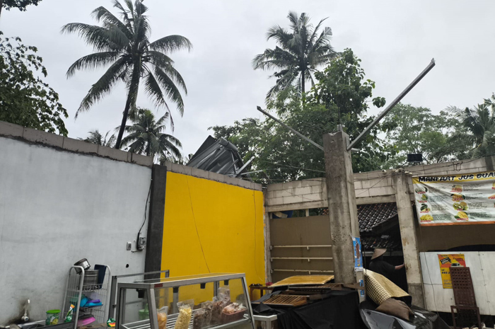 RUSAK: Seorang warga mengecek kondisi bangunan toko di Desa Bulungan, Pakis Aji yang atapnya hilang disapu angin kencang, Kamis (9/1).