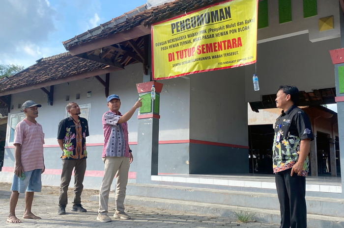 TUTUP: Kepala Bisang Pasar DindagkopUKM Margo Yuwono memasang spanduk pemberitahuan ditutupnya Pasar Hewan Pon Blora, Kamis (9/1).