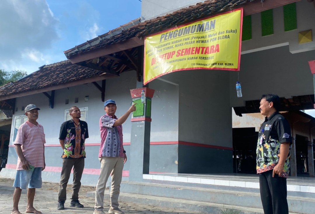 TUTUP: Kepala Bidang Pasar DindagkopUKM Margo Yuwono memasang spanduk pemberitahuan ditutupnya Pasar Hewan Pon Blora baru-baru ini.