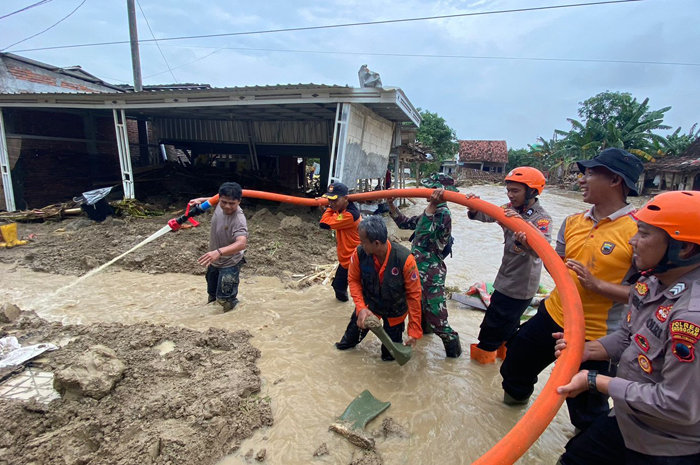 BERSIHKAN LUMPUR: Anggota Polri TNI BPBD dan warga membersihkan lumpur akibat banjir di jalan Desa Baturagung, Kecamatan Gubug kemarin.