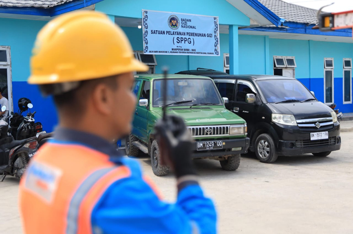 Petugas Pelayanan Teknik (Yantek) tengah berkoordinasi dengan tim teknis melalui Handy Talky saat memastikan kondisi kelistrikan Dapur MBG di Kelurahan Perhentian Marpoyan, Pekanbaru.