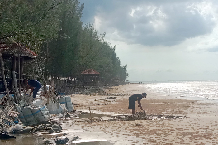 PENANGANAN SEMENTARA: Warga sekitar pantai memasukkan pasir ke dalam karung untuk menahan ombak, agar abrasi tidak meluas baru-baru ini.
