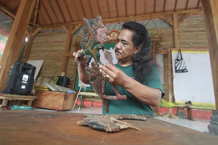 DIAMBANG KEPUNAHAN: Ki Hadi Purwanto membersihkan wayang klitik koleksinya di sanggarnya.