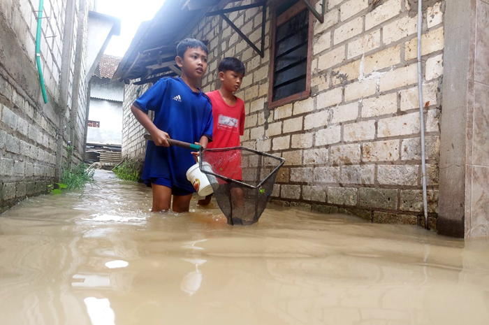 TERGENANG: Anak-anak menjaring ikan di tengah banjir Desa Doropayung, Juwana, Sabtu (8/2).