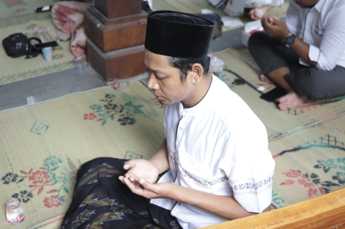 Ilustrasi: Seorang lagi khusuk berdoa dalam khataman al-Quran.