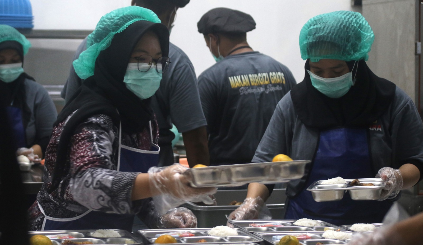 HIGIENIS: Petugas SPPG 002 mem-packing paket makanan bergizi untuk didistribusikan ke sekolah-sekolah.