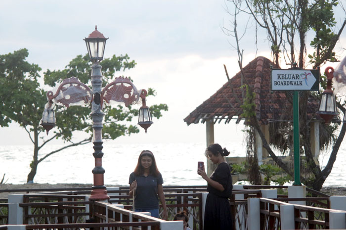 PANORAMA MENARIK: Wisatawan berjalan di boardwalk yang jadi salah satu ikon Pantai Bandengan.