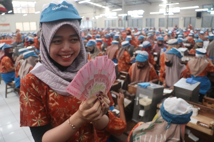 SEKARANG TIDAK TUNAI: Salah satu buruh PT Djarum menunjukkan uang THR yang dibagikan secara tunai tahun lalu. Kini, penyalurannya sudah melalui transfer ke rekening bank