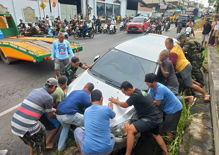 RINGSEK: Para warga bantu proses evakuasi mobil yang masuk ke saluran air