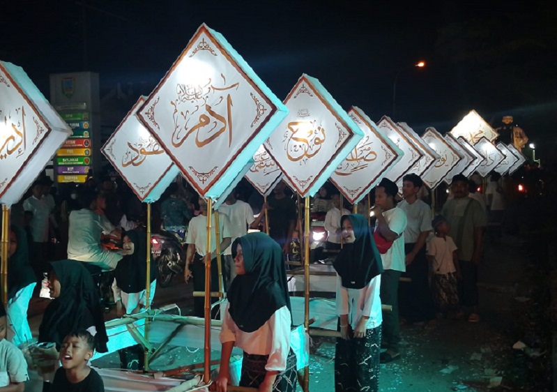 KONDUSIF: Peserta takbiran di Desa Wates, Kecamatan Undaan memegangi atribut yang bertuliskan huruf arab sambil keliling di gang.