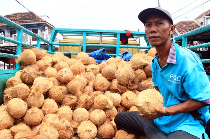PENUHI PERMINTAAN: Tukang angkut menurunkan kelapa dari atas truk untuk diambil para pengecer di pasar Rembang kota.