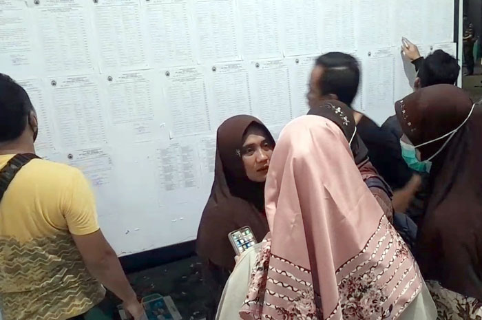 DILIHAT: Peserta seleksi pegawai di RSUD RAA Soewondo mengecek papan pengumuman di RS setempat tadi malam.