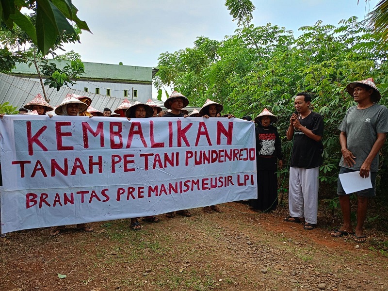 BERDIRI: Petani Pundenrejo, Tayu memegang spanduk di lahan sengketa belum lama ini.