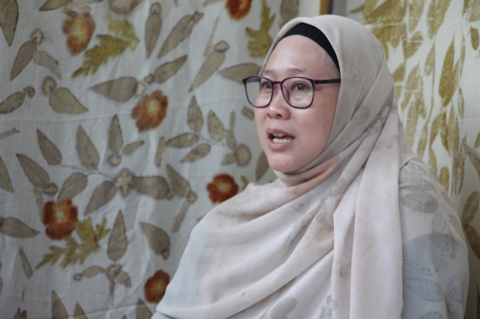 KARYA NYATA: Nunung Noor Khamimah dengan background perajin ecoprint memperlihatkan salah satu produk kain ecoprint miliknya.
