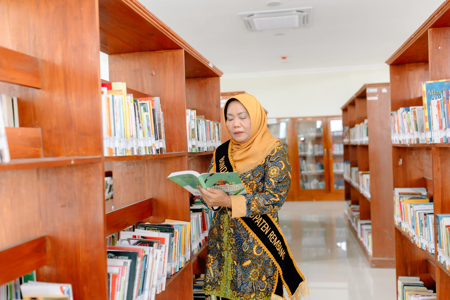 DITUNGGU: Bunda Literasi Kabupaten Rembang, Musringah Harno  membaca buku di ruang perpustakaan daerah. Mengajak putra-putri asli Kabupet Rembang ikuti menjadi duta literasi.