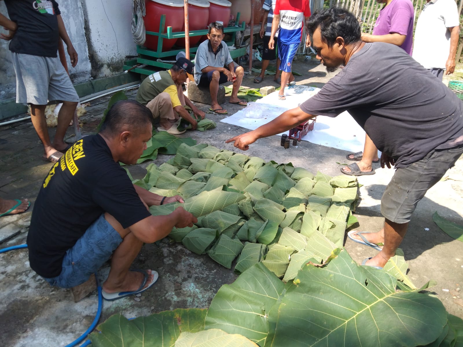 KURANGI PLASTIK : Panitia kurban di Masjid Al Hikmah membungkus daging memakai daun jati.