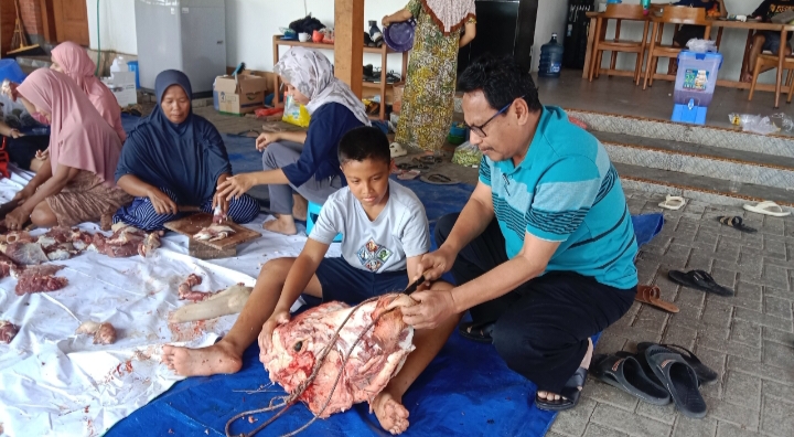 POTONG DAGING : Bupati Rembang Harno membantu cucunya memotong daging bagian kepala sapi.