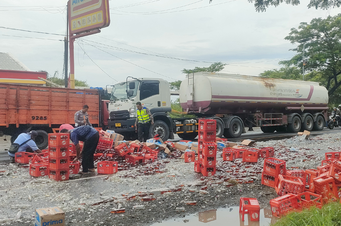 AMBYAR: Petugas Satlantas Polres Rembang membersihkan botol beling berisikan teh yang ambyar ditengah jalan pantura Pasarbanggi, Senin (9/6).&nbsp;