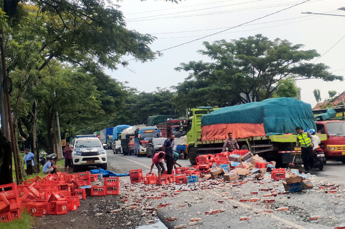 AMBYAR: Petugas Satlantas Polres Rembang membersihkan botol beling berisikan teh yang ambyar ditengah jalan pantura Pasarbanggi, Senin (9/6).&nbsp;