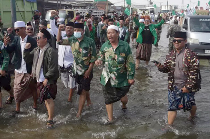 Sejumlah warga Nahdliyin berjalan menerobos genangan banjir rob menuju acara Istighatsah Kemanusiaan di Jalur Pantura, Kecamatan Sayung, Kabupaten Demak, Jawa Tengah, Minggu (15/6).