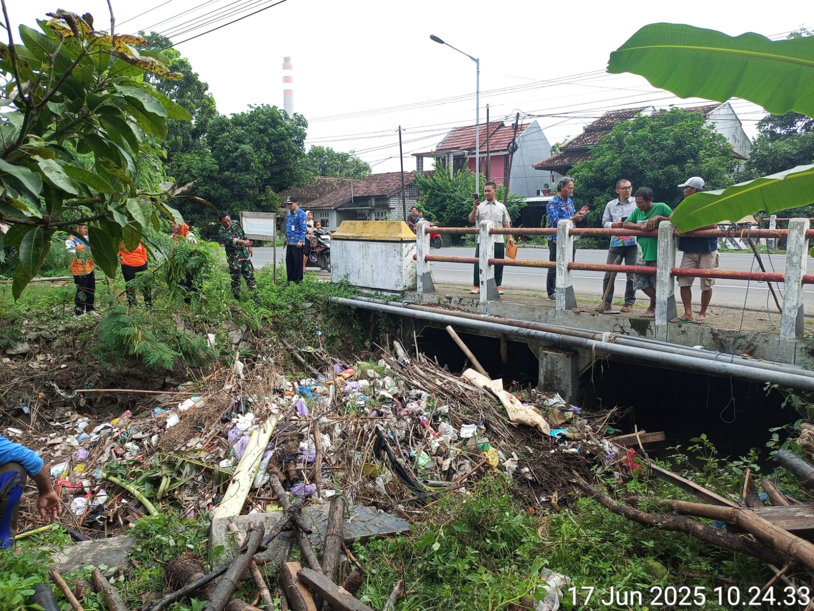 KERJA BAKTI: Warga membantu kerja bakti urai sampah yang tersumbat, satu sisi stakeholder terkait mengecek kondisi di Trahan dari atas jembatan, Selasa lalu (17/6).