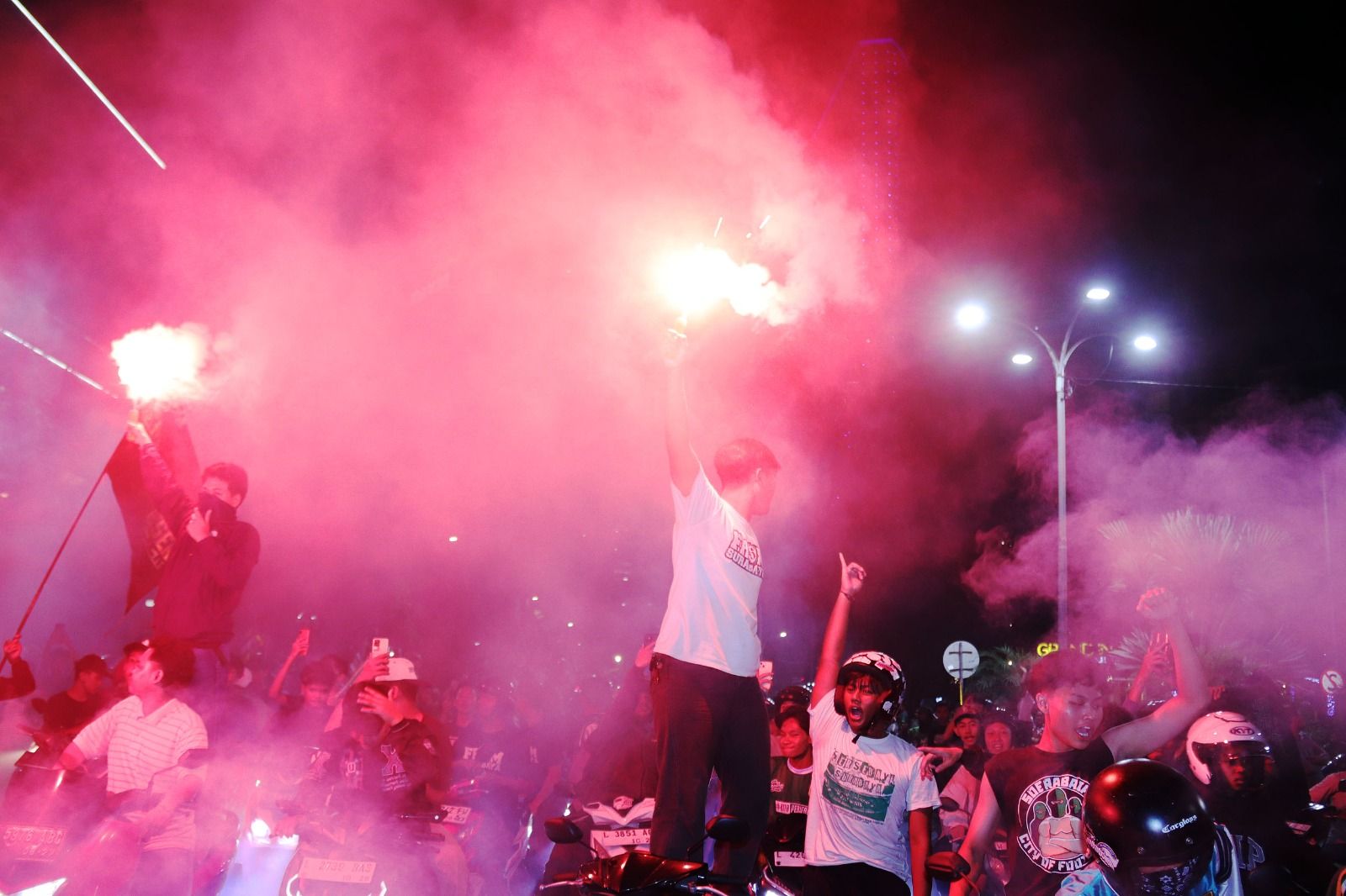 MENYALA : Suporter menyalakan flare sepanjang Jalan Gubernur Suryo, Surabaya. Beberapa kembang api juga menyalak di lokasi. (ANDY SATRIA/RADAR SURABAYA) (ANDY SATRIA/RADAR SURABAYA)