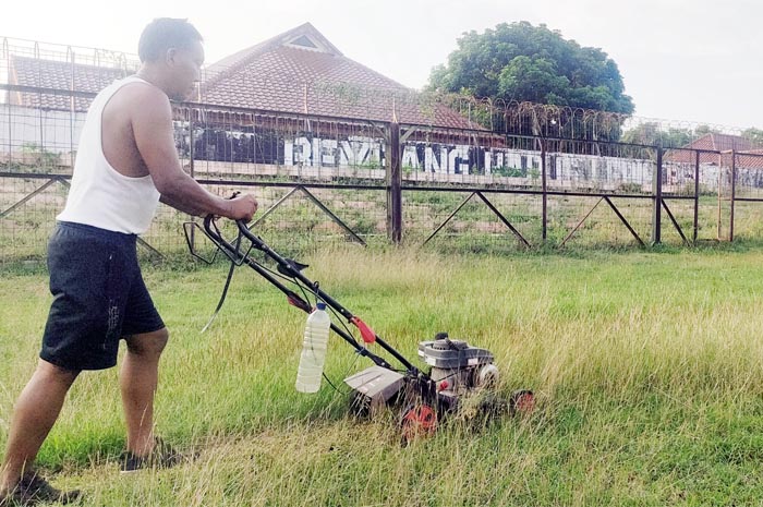 POTONG RUMPUT: Petugas Stadion Krida Rembang mulai membersihkan rumput stadion kemarin.