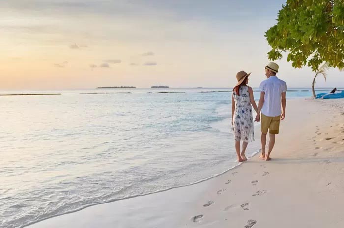 Ilustrasi pasangan baru saat honeymoon di pantai.