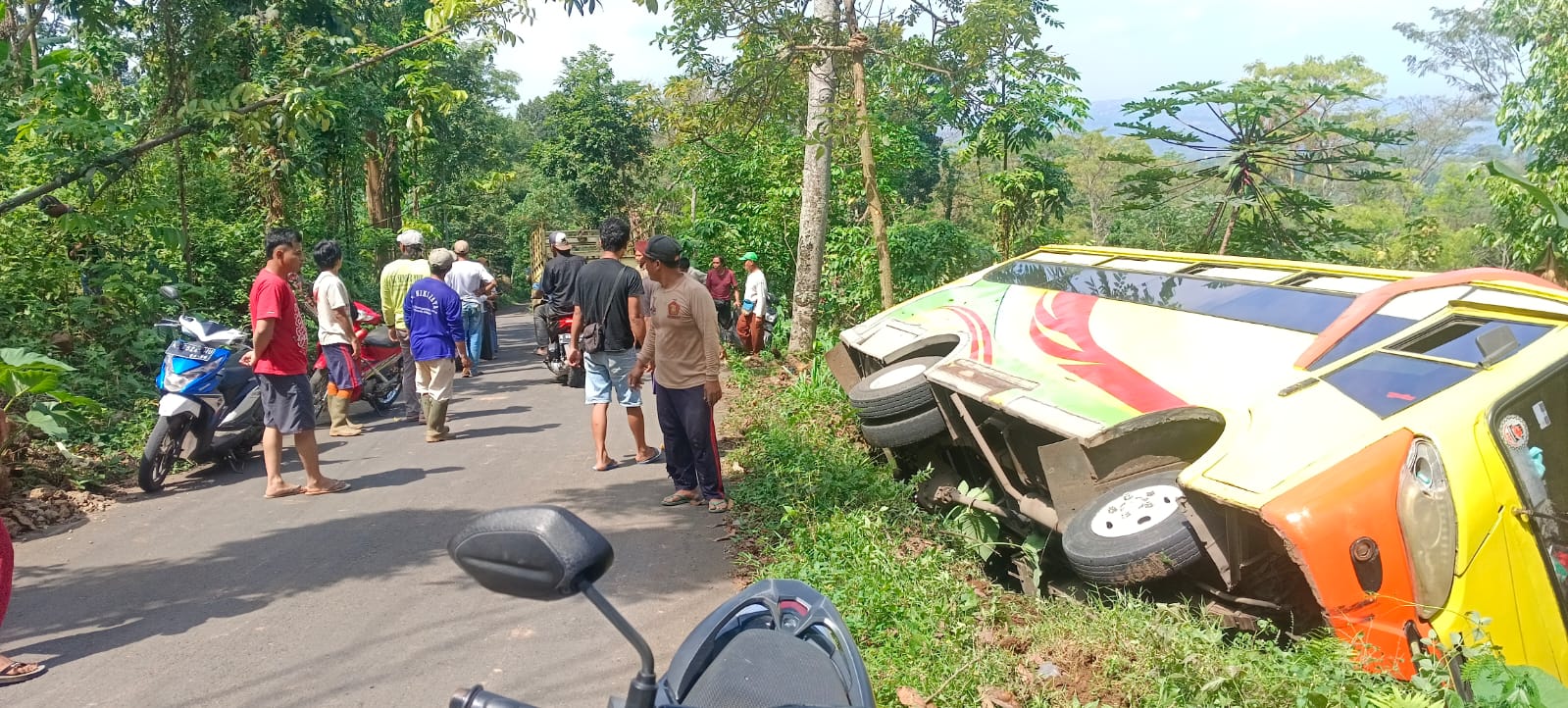 INSIDEN: Warga bergotong royong membantu penumpang bus mini yang mengalami insiden terguling di Japan, siang ini. (DESTANA JAPAN UNTUK RADAR KUDUS)